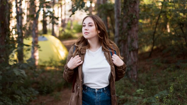 Ragazza a metà tiro con lo zaino davanti alla tenda