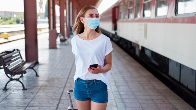 Ragazza a metà tiro con maschera che cammina lungo il treno