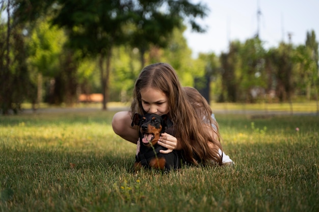 Ragazza a tutto campo che bacia il cane sulla testa