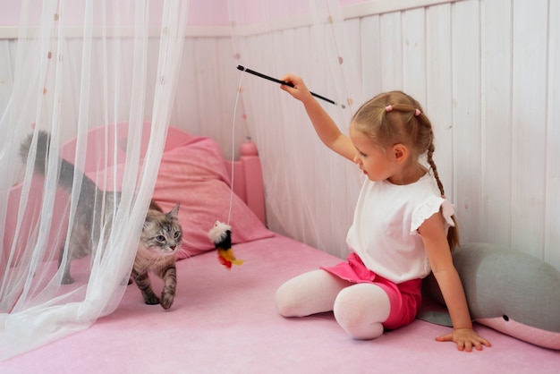 Ragazza a tutto campo che gioca con il gatto