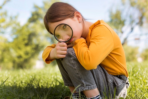 Ragazza a tutto campo con lente d'ingrandimento