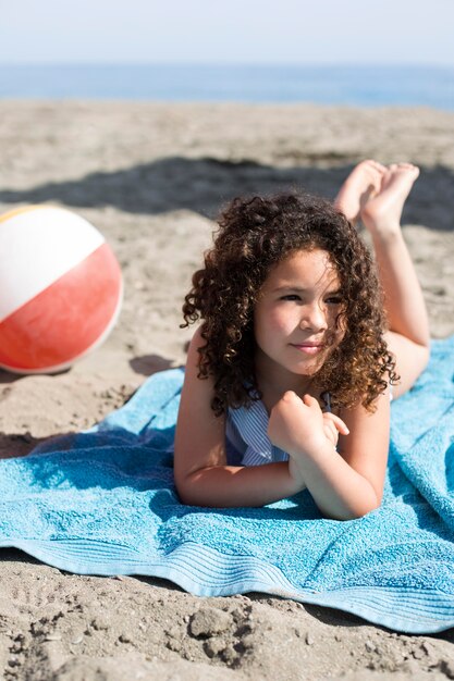 Ragazza a tutto campo sdraiata sulla spiaggia