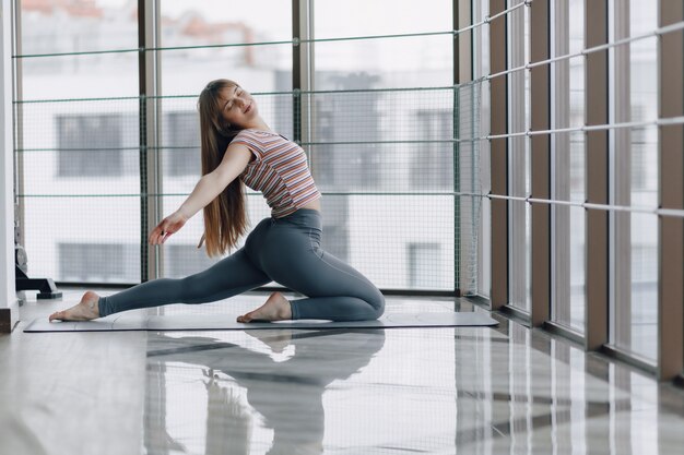 Ragazza abbastanza attraente che fa yoga in una stanza luminosa