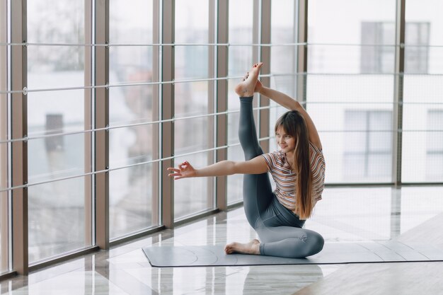 Ragazza abbastanza attraente che fa yoga in una stanza luminosa