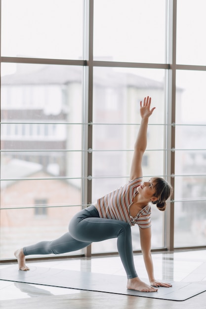 Ragazza abbastanza attraente che fa yoga in una stanza luminosa