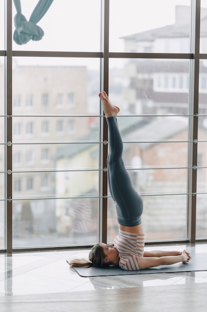 Ragazza abbastanza attraente che fa yoga in una stanza luminosa