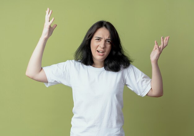 Ragazza abbastanza caucasica giovane infastidita che solleva le mani isolate su priorità bassa verde oliva