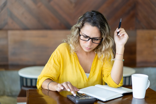 Ragazza accigliata graziosa che conta bilancio