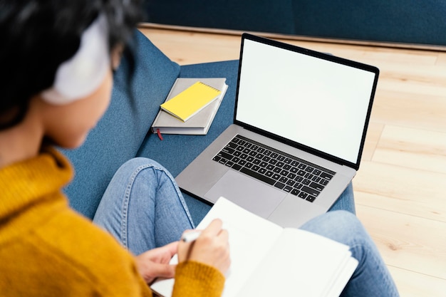 Ragazza adolescente con cuffie e laptop durante la scuola in linea