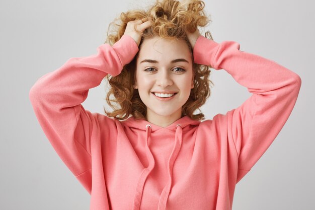 Ragazza adolescente felice spensierata sorridente, toccando i capelli