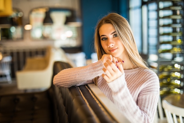 Ragazza adolescente studente modello abbastanza giovane vestita in jeans nella caffetteria tiene la tazza di tè e caffè nelle sue mani