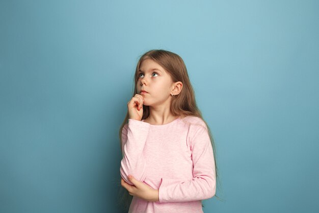 ragazza adolescente triste su sfondo blu studio. Le espressioni facciali e le emozioni delle persone concetto.