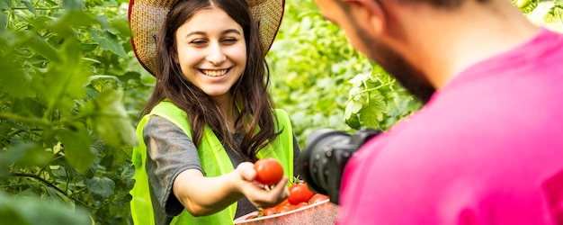 Ragazza adorabile che sorride alla macchina fotografica e che tiene i pomodori