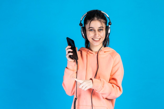 Ragazza adorabile che tiene il telefono e punta il dito su di esso