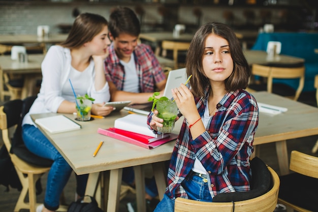 Ragazza affascinante con i compagni di classe al tavolo