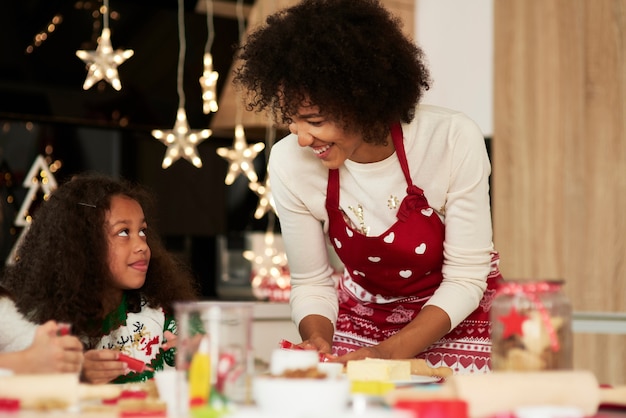 Ragazza africana che cucina i biscotti con l'aiuto di sua madre