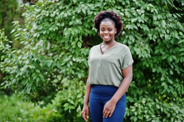 Ragazza africana in posa per strada di città indossa camicetta verde e pantaloni blu