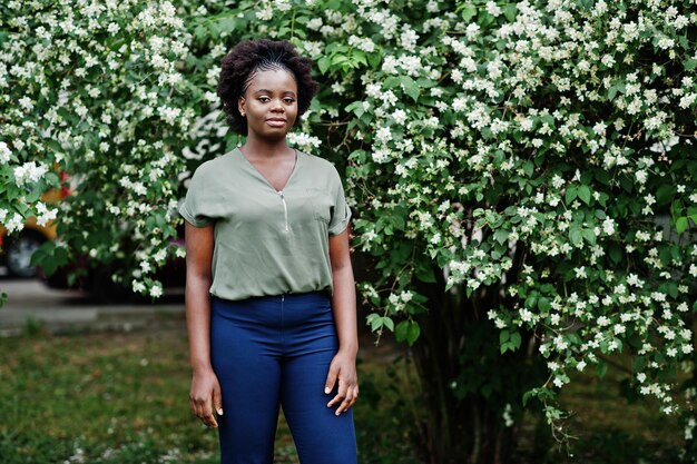 Ragazza africana in posa per strada di città indossa camicetta verde e pantaloni blu