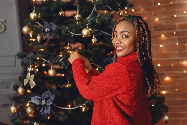 Ragazza africana in un addobbo natalizio / Donna in un maglione rosso. Anno nuovo concetto.