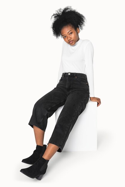 Ragazza afroamericana in dolcevita bianco e jeans neri per il servizio di abbigliamento invernale