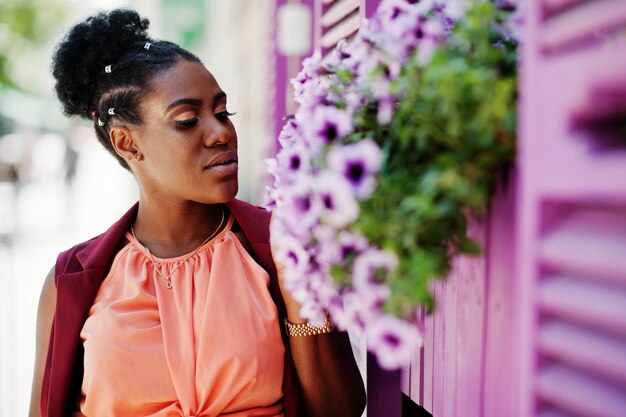 Ragazza afroamericana posata contro le finestre viola all'aperto