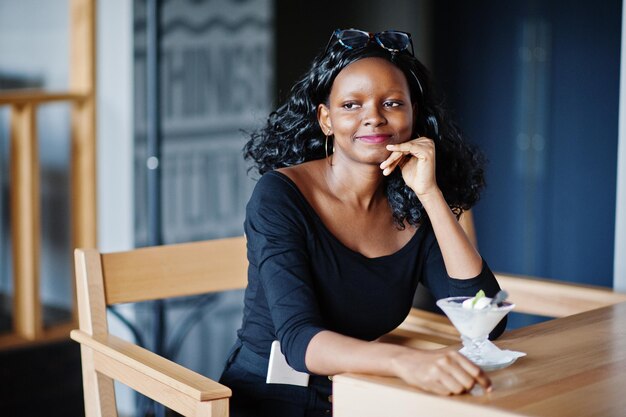 Ragazza afroamericana seduta al bar e mangiare il gelato