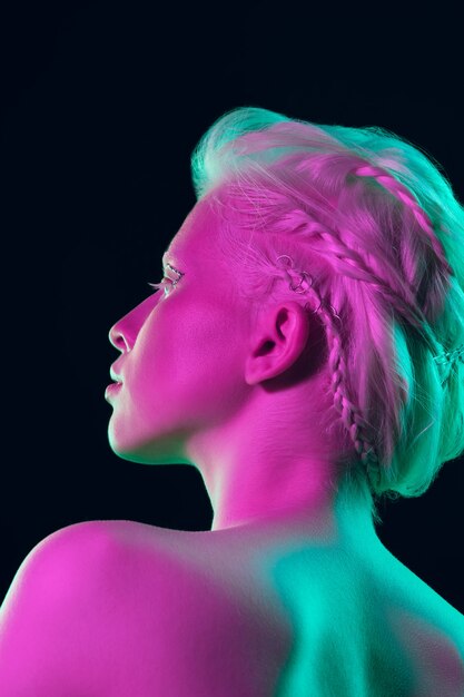 Ragazza albino con pelle bianca, labbra naturali e capelli bianchi in luce al neon isolata su sfondo nero studio.