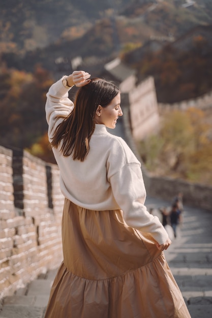 Ragazza alla moda che visita la Grande Muraglia cinese vicino a Pechino durante la stagione autunnale.