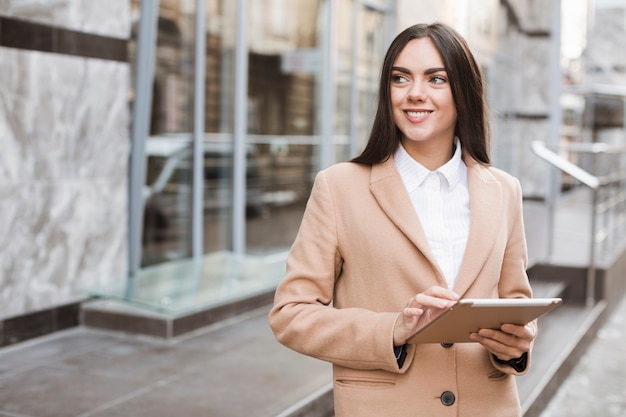 Ragazza alla moda contenta facendo uso della compressa