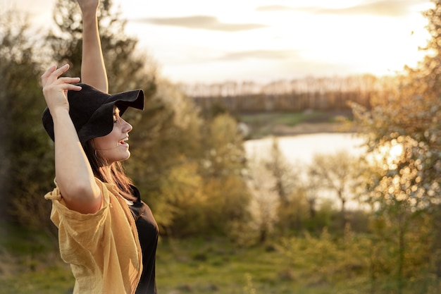 Ragazza alla moda in stile casual sorride e guarda il tramonto.