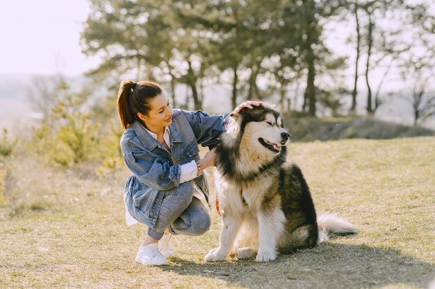 Ragazza alla moda in un campo soleggiato con un cane