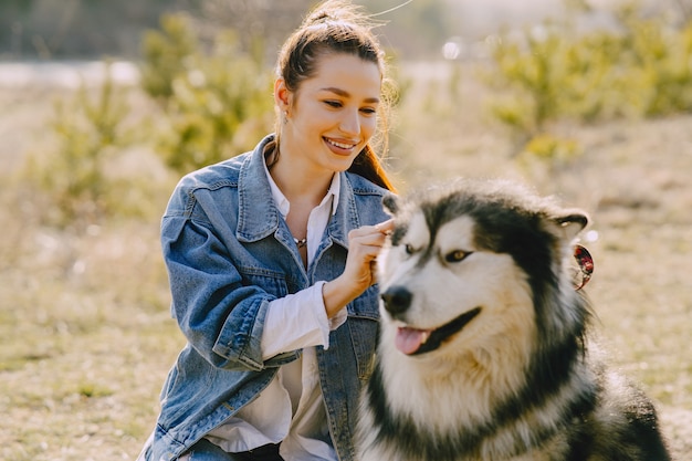 Ragazza alla moda in un campo soleggiato con un cane