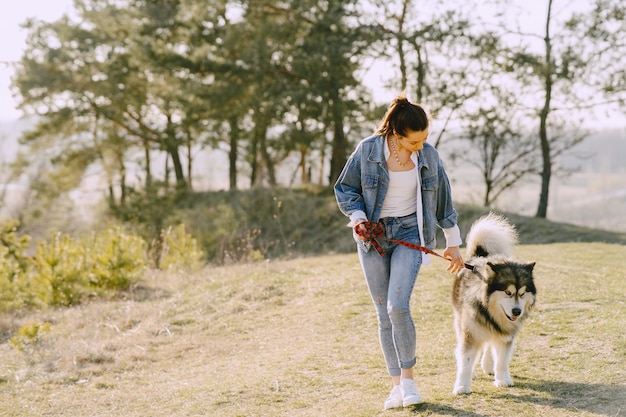 Ragazza alla moda in un campo soleggiato con un cane