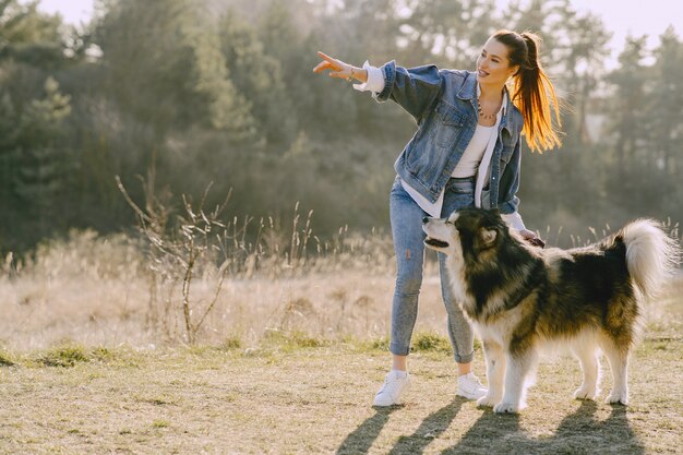 Ragazza alla moda in un campo soleggiato con un cane