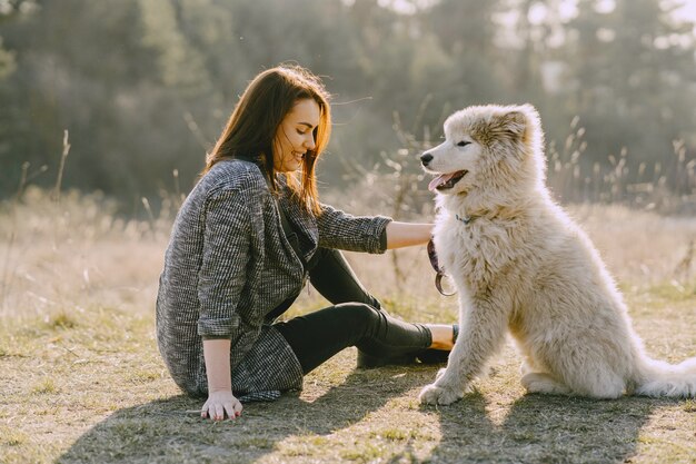 Ragazza alla moda in un campo soleggiato con un cane