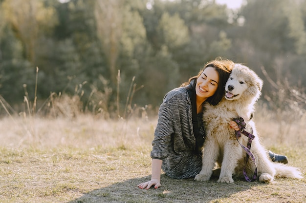 Ragazza alla moda in un campo soleggiato con un cane