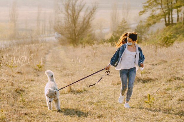 Ragazza alla moda in un campo soleggiato con un cane