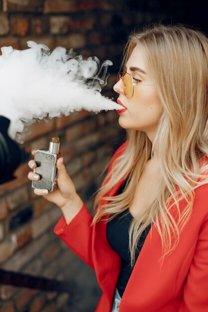 Ragazza alla moda in una città con vape