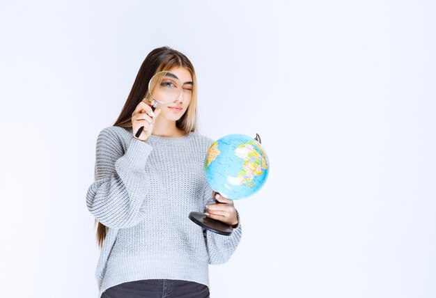 Ragazza alla ricerca di posizioni in tutto il mondo con una lente d'ingrandimento.