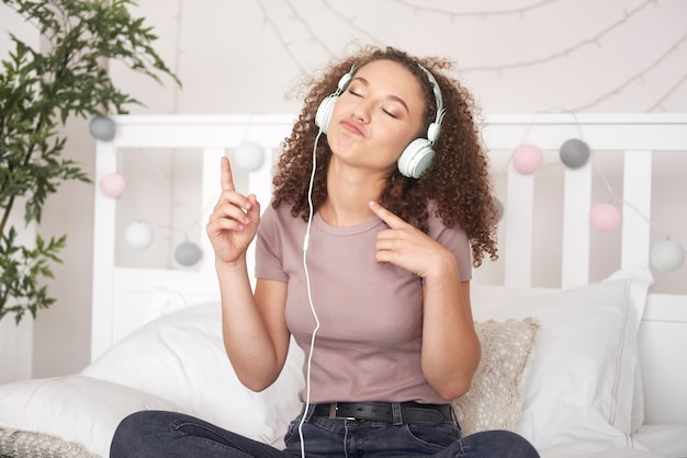 Ragazza allegra che ascolta musica e balla sul letto