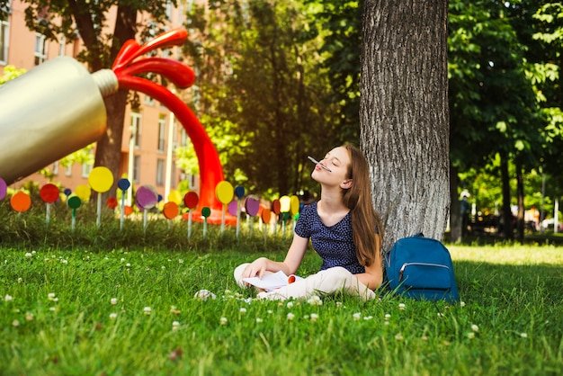 Ragazza allegra con gli studi sul prato inglese