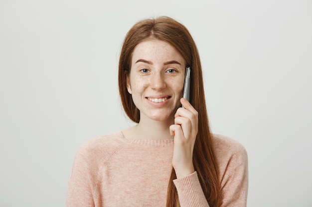 Ragazza allegra rossa con le lentiggini, sorridente e parlando al telefono spensierata