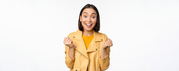 Ragazza asiatica sorpresa e felice che guarda con la faccia felice di gioire vincendo celebrando la vittoria e tr