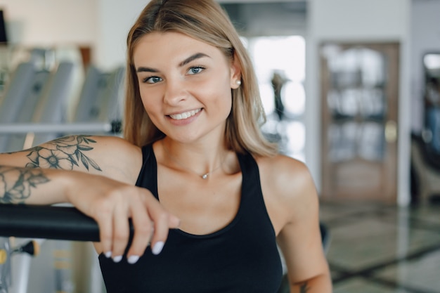 Ragazza atletica attraente che sta l'attrezzatura vicina della palestra. uno stile di vita sano.