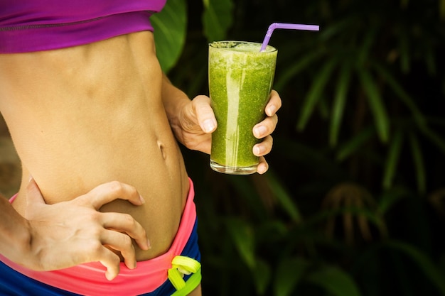 Ragazza atletica che tiene un frullato verde