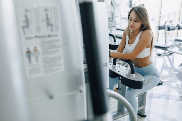 Ragazza attraente di sport che riposa sul simulatore e che sorride piacevolmente.