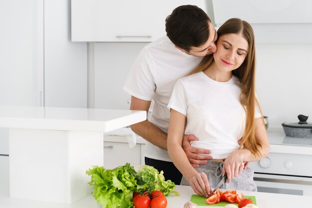 Ragazza baciante del ragazzo mentre cucinando