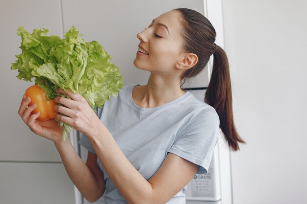 Ragazza bella e sportiva in una cucina con verdure