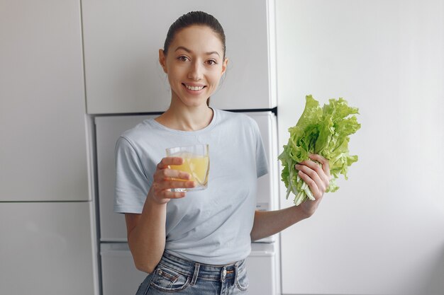 Ragazza bella e sportiva in una cucina con verdure