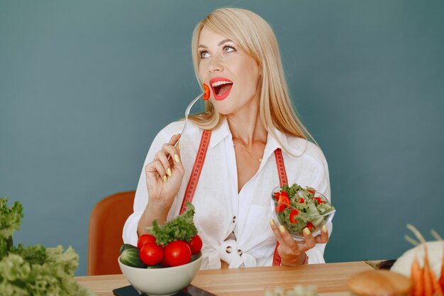 Ragazza bella e sportiva in una cucina con verdure